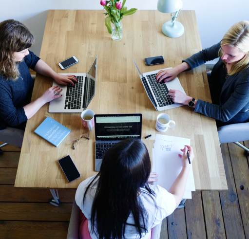 Overhead of employees working on laptops around a table