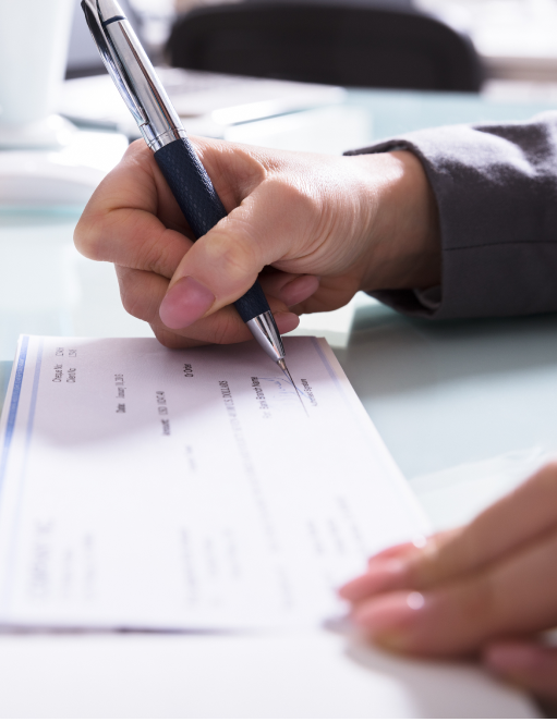 Woman signing paychecks from PEO services Woman signing paychecks from PEO services