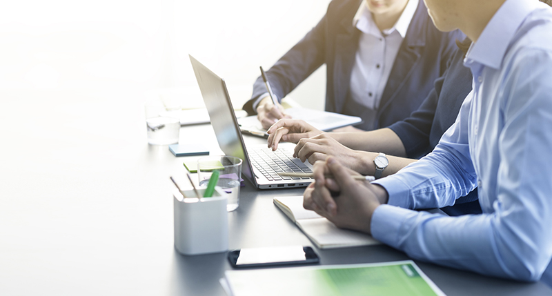 Professional business team working together at desk An image of two individuals working and talking around a laptop.
