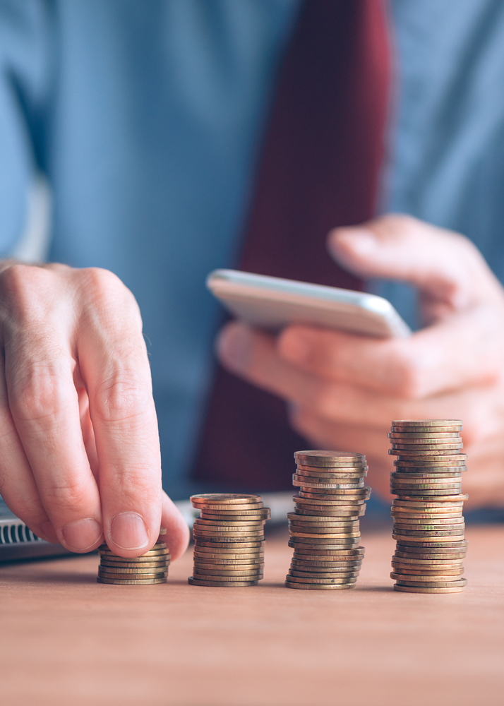 financial-programs Hands stacking coins and holding a phone