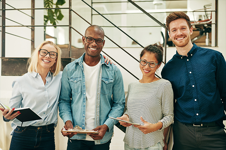 110321 DEI for your business in 2022 Emails_BLOG_IMAGE Employees smiling while holding clipboards