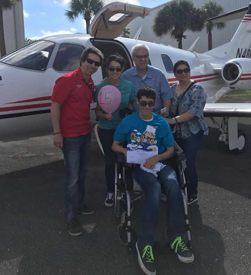 Challenge Air volunteer and a family including a child with special needs next to an aircraft